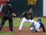 Oakland Athletics' Jed Lowrie waits for the ball to tag out Seattle Mariners' Jean Segura, right, in the first inning of a baseball game Monday, Aug. 13, 2018, in Oakland, Calif.