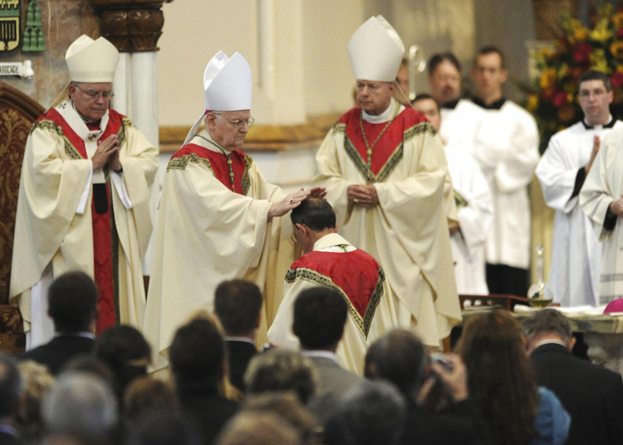 FILE – In this Oct. 1, 2012, file photo, the Most Rev. Donald Trautman, second from left, retiring bishop of Erie, Pa., prays and lays his hands on the head of Monsignor Lawrence T. Persico, kneeling, the bishop-elect of Erie, Pa., during Persico's rite of ordination at St. Peter Cathedral in Erie, Pa. The Most Rev. Charles J. Chaput, left, archbishop of Philadelphia, served as principal consecrator during the service, and the Most Rev. Lawrence E. Brandt, center, bishop of Greensburg, Pa., served as co-consecrator with Trautman. A grand jury report released Tuesday, Aug. 14, 2018, documenting seven decades of child sexual abuse by Roman Catholic priests in Pennsylvania says Trautman allowed priests to continue restricted or regular duties despite credible allegations of abuse, was dishonest to the public or other officials about the diocese's knowledge of abuse and reassigned priests with credible accusations to keep them in the ministry. Trautman and his lawyer deny the bishop ever covered up sexual abuse by priests.