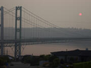 The sun is seen through smoky air as it sets, Sunday, Aug. 19, 2018, behind the Narrows Bridge in Tacoma, Wash. Poor air quality will be common across parts of the Pacific Northwest this week as winds push smoke from surrounding wildfires into the region, forecasters and regulators said, and air quality alerts are in effect for much of Washington state through Wednesday. (AP Photo/Ted S.