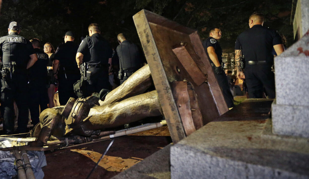 Police stand guard after the confederate statue known as Silent Sam was toppled by protesters on campus at the University of North Carolina in Chapel Hill, N.C., Monday, Aug. 20, 2018.