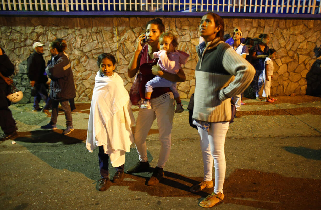 Residents stand outside their apartments in a street near the "Tower of David" skyscraper, which suffered an inclination after a powerful earthquake shook eastern Venezuela, causing buildings to be evacuated in the capital of Caracas, Venezuela, Tuesday, Aug. 21, 2018. The quake was felt as far away as Colombia's capital and in the Venezuelan capital office workers evacuated buildings and people fled homes.