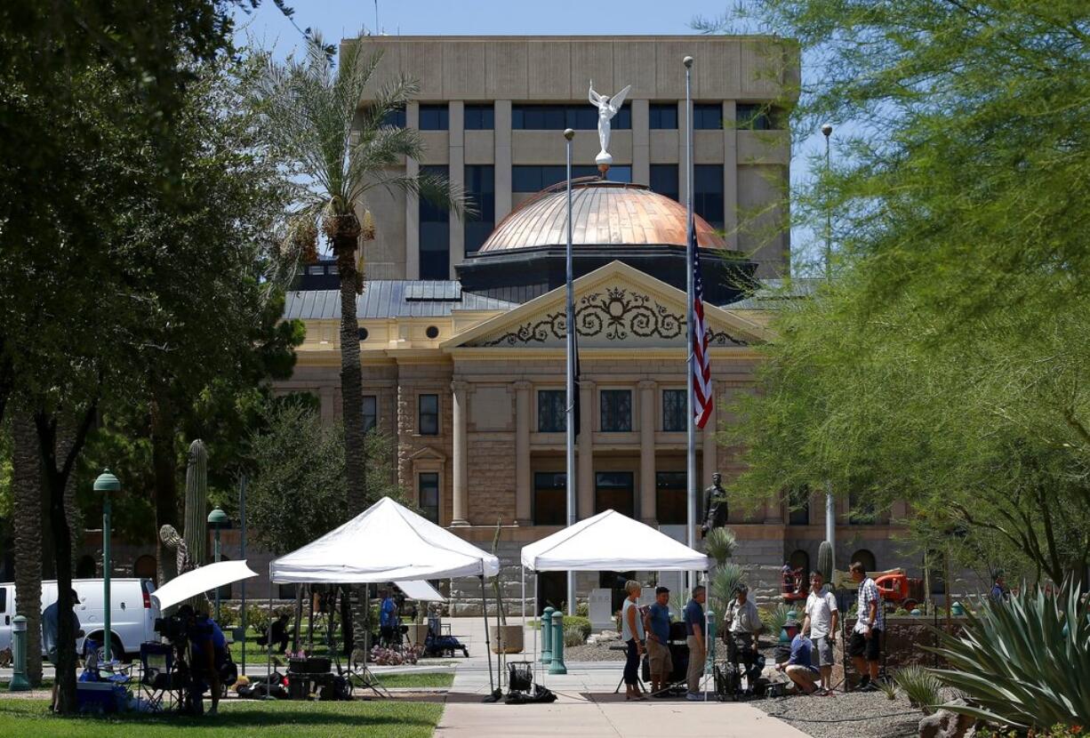 As flags fly at half-staff at the Arizona Capitol in memory of the late Arizona Republican Sen. John McCain, television crews broadcast live Sunday, Aug. 26, 2018, in Phoenix. McCain, the war hero who became the GOP's standard-bearer in the 2008 election, has died at the age of 81, Saturday, Aug. 25, 2018, after battling brain cancer. (AP Photo/Ross D.