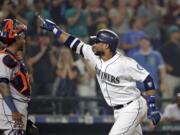 Seattle Mariners’ Robinson Cano, right, points toward the stands as he passes Houston Astros catcher Martin Maldonado at home on his three-run home run in the eighth inning of a baseball game, Monday, Aug. 20, 2018, in Seattle.