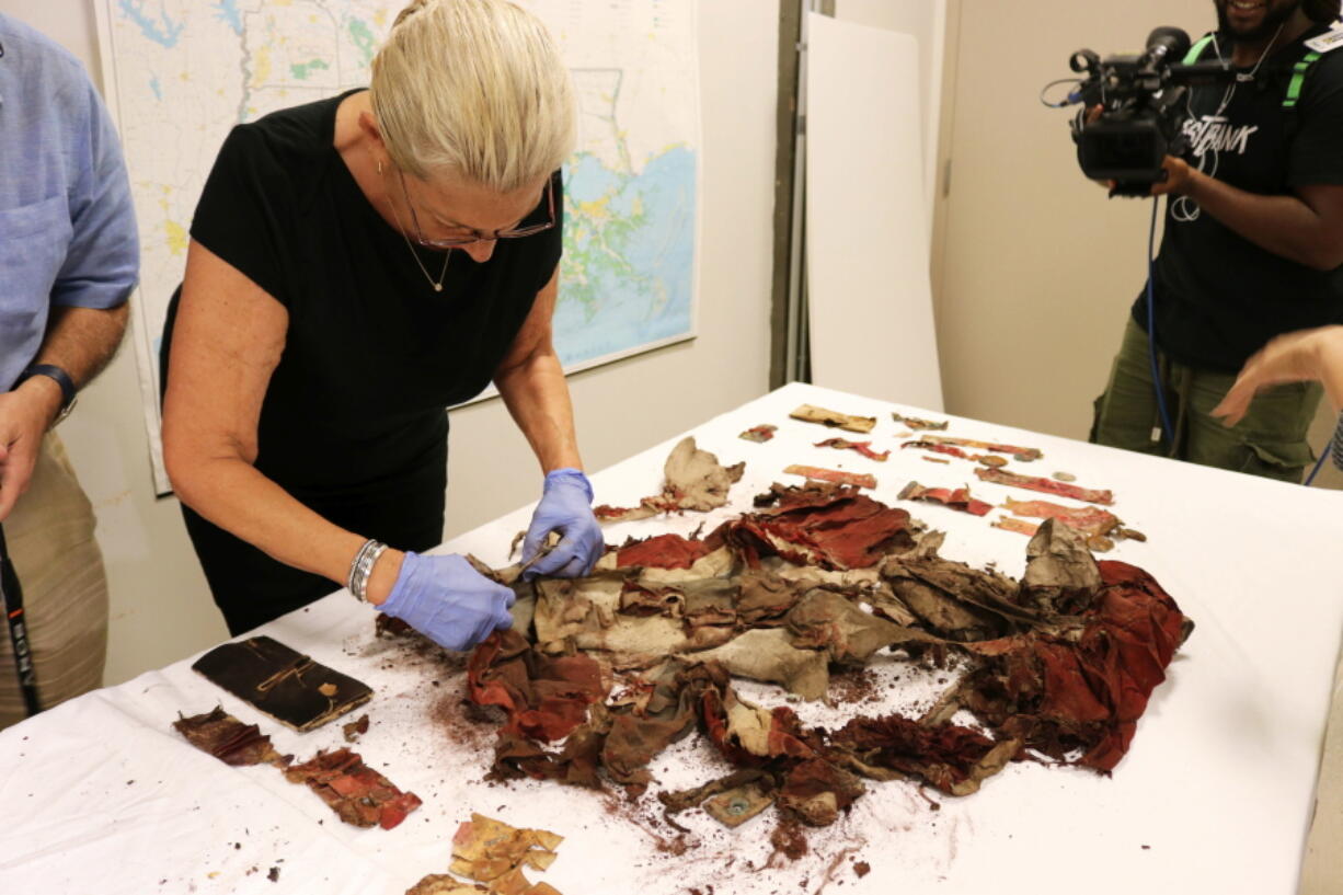 Textile conservator Jessica Hack of New Orleans examines a “wet and shredded” flag that topped artifacts in a 1913 time capsule unpacked Friday at a Louisiana State Museum storage building in New Orleans.