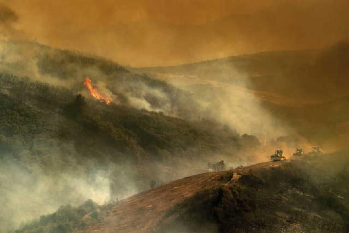 In this Tuesday, July 31, 2018, file photo, bulldozer operators and their machines build containment lines while battling the River Fire in Lakeport, Calif. Authorities say a rapidly expanding Northern California wildfire burning over an area the size of Los Angeles has become the state's largest blaze in recorded history. It's the second year in a row that California has recorded the state's largest wildfire.