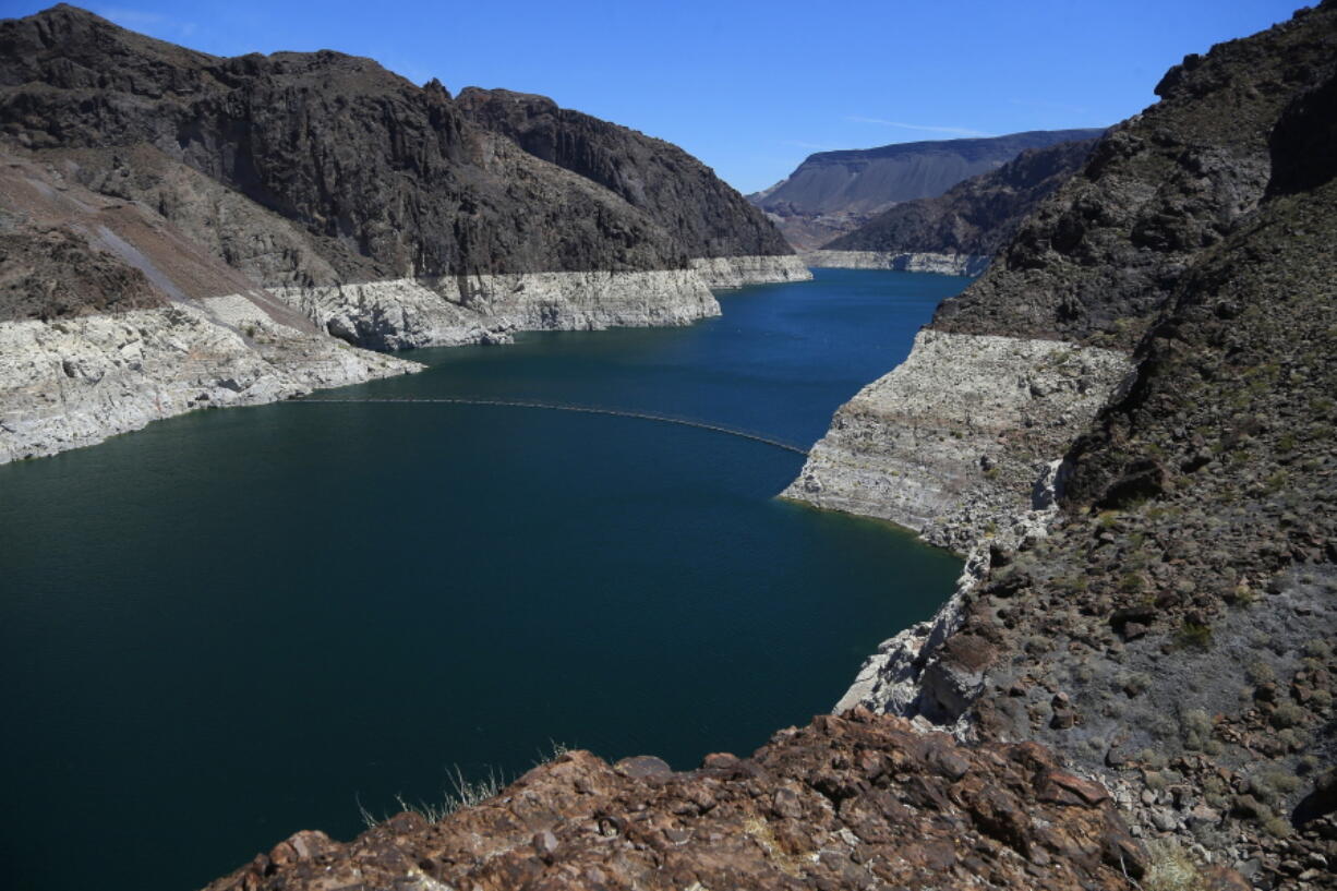 FILE - In this May 31, 2018, file photo, the low level of the water line is shown on the banks of the Colorado River in Hoover Dam, Ariz. U.S. officials say the chances of a shortage in the vital Colorado River system have risen to 57 percent in 2020. (AP Photo/Ross D.