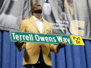 Former wide receiver Terrell Owens holds a street sign after a road was named for him following his Pro Football Hall of Fame speech, Saturday, Aug. 4, 2018, in Chattanooga, Tenn. Instead of speaking at the Hall of Fame events in Canton, Ohio, Owens celebrated his induction at the University of Tennessee at Chattanooga, where he played football and basketball and ran track.