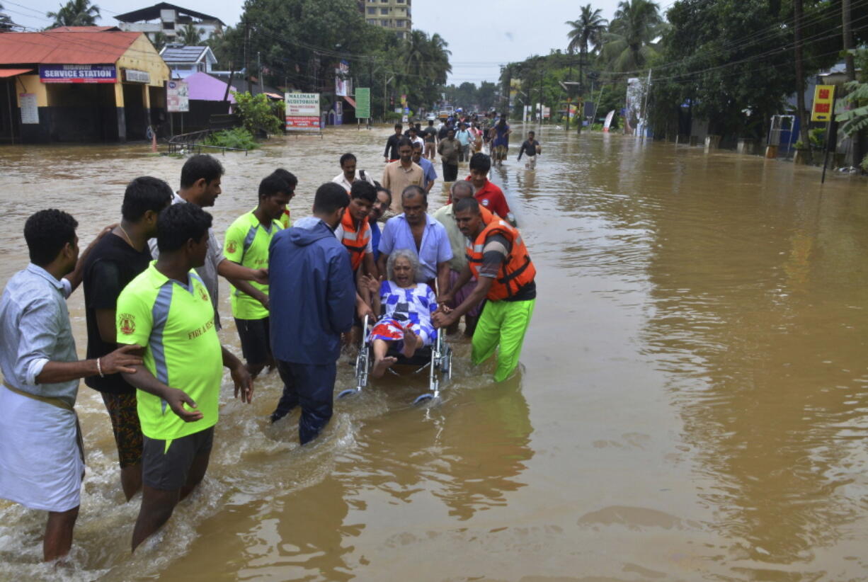 In this Thursday, Aug. 16, 2018 photo, an elderly woman is evacuated towards safer area in Thrissur, in the southern Indian state of Kerala. Rescuers used helicopters and boats on Friday to evacuate thousands of people stranded on their rooftops following unprecedented flooding in the southern Indian state of Kerala that left more than 100 dead.