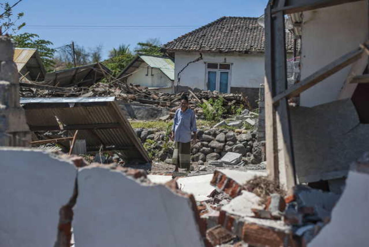 A man inspects a village destroyed by a strong earthquake in Kayangan, Lombok Island, Indonesia, Monday, Aug. 6, 2018. Indonesian authorities said Monday that rescuers still haven't reached some devastated parts of the tourist island of Lombok after the powerful earthquake flattened houses and toppled bridges, killing large number of people and shaking neighboring Bali.