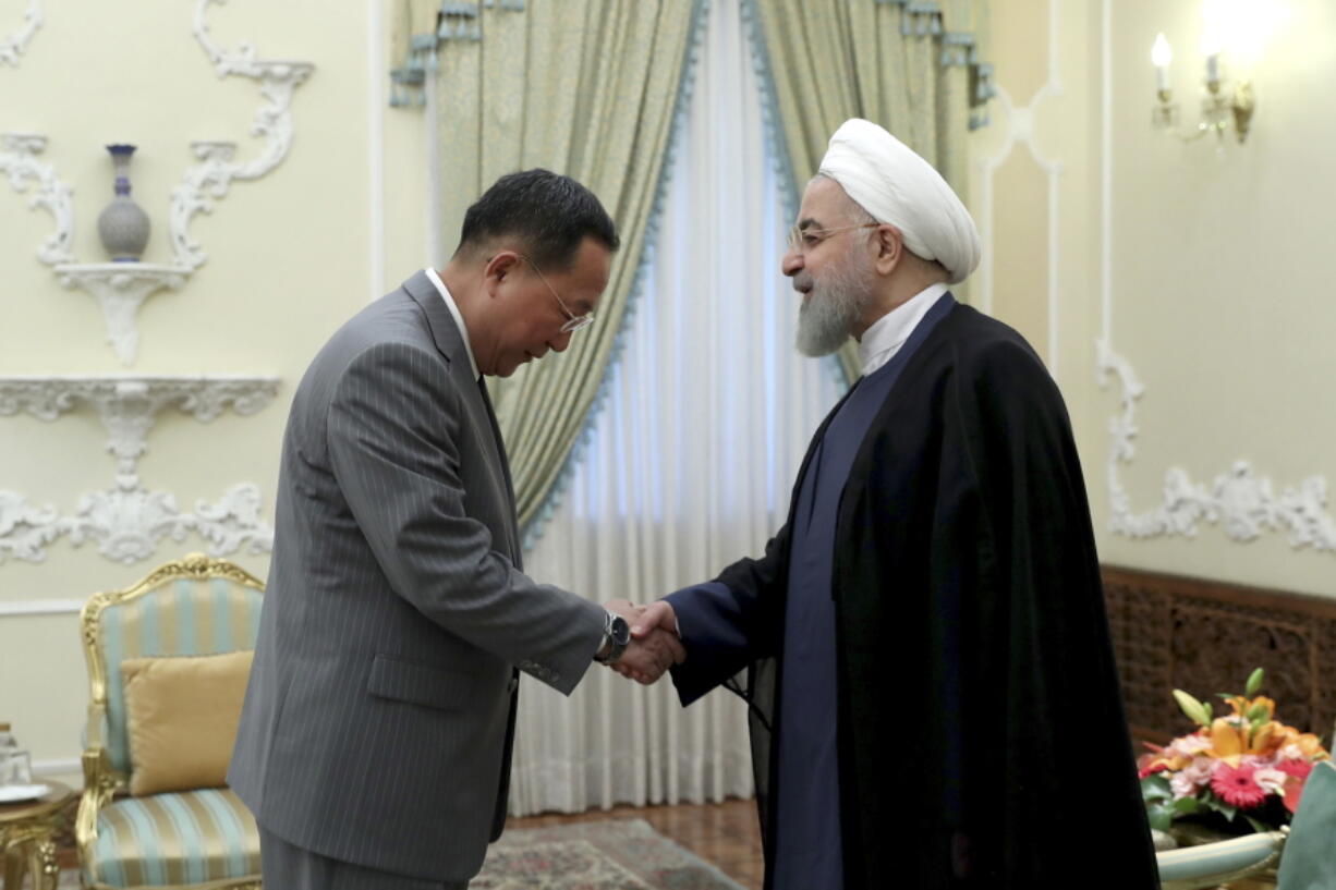 In this photo released by an official website of the office of the Iranian Presidency, President Hassan Rouhani, right, greets North Korean Foreign Minister Ri Yong Ho at the start of their meeting, at the presidency office, in Tehran, Iran, Wednesday, Aug. 8, 2018.