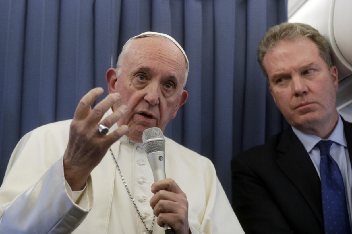 Pope Francis, flanked by Vatican spokesperson Greg Burke, listens to a journalist’s question during a press conference aboard of the flight to Rome at the end of his two-day visit to Ireland, Sunday, Aug. 26, 2018.