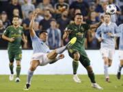 Sporting Kansas City defender Roger Espinoza, front left, clears the ball away from Portland Timbers midfielder David Guzman, front right, during the second half of an MLS soccer match in Kansas City, Kan., Saturday, Aug. 18, 2018. (AP Photo/Colin E.