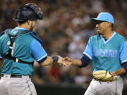 Seattle Mariners catcher Mike Zunino (3) and Edwin Diaz celebrate after the Mariners defeated the Arizona Diamondbacks 6-3 during a baseball game Friday, Aug. 24, 2018, in Phoenix.