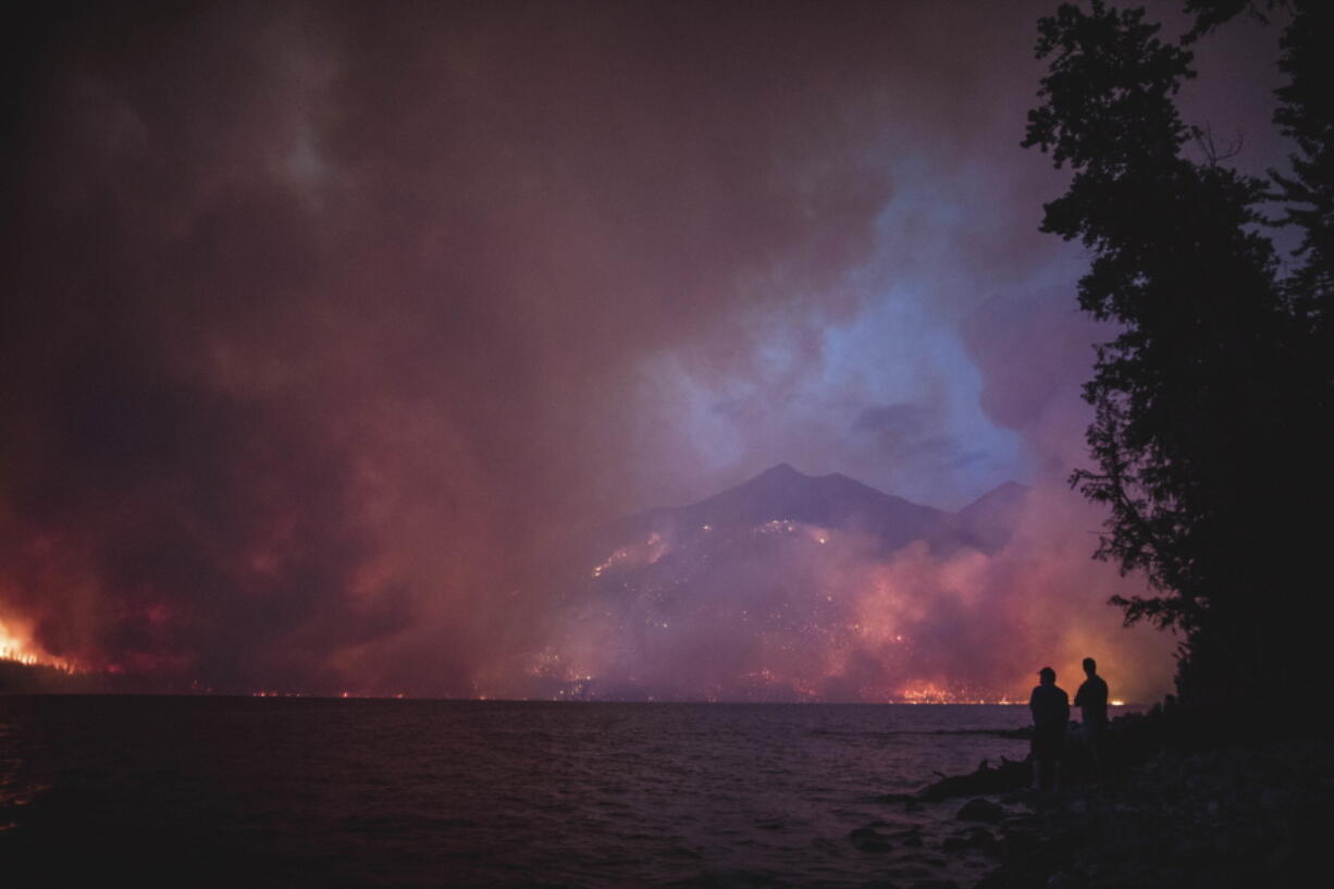 FILE - This Sunday, Aug. 12, 2018 file photo provided by the National Park Service shows the Howe Ridge Fire from across Lake McDonald in Glacier National Park, Mont. The wildfire in northwest Montana’s Glacier National Park is forcing evacuations and has burned within a mile of the scenic Going-to-the-Sun Road. The Missoulian reported Sunday, Aug. 19, 2018 that the Howe Ridge fire had grown to more than 12 square miles, and shifting winds are forecast over the next day and a half.