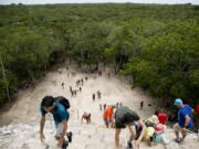 Tourists climb a temple at the archeological site of Coba, in Mexico’s Yucatan Peninsula. Whether you’re planning a trip to a country across the globe or packing for a weekend at a local campground, you can have a debt-free vacation with careful planning.