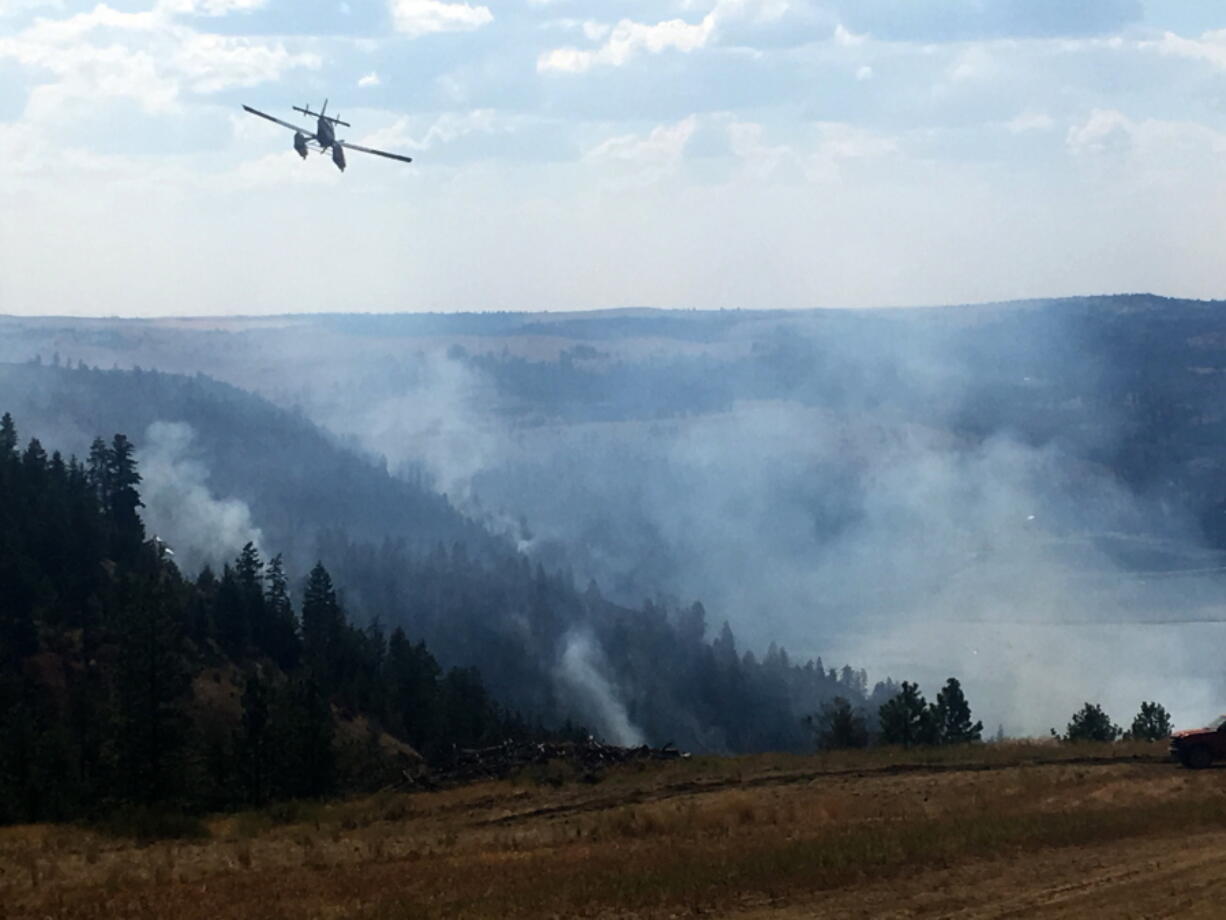 A Fire Boss plane continues to battle a wildfire in Eastern Washington on Sunday.