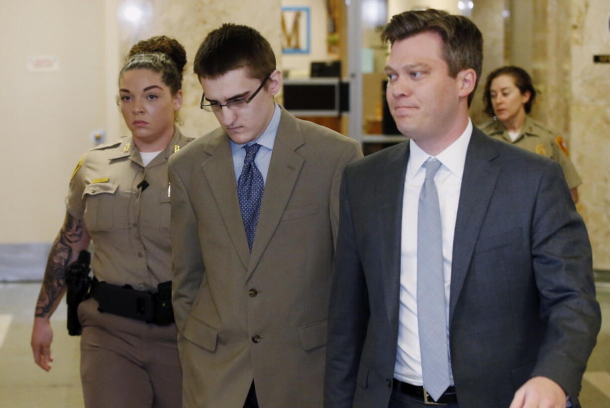 FILE - In this Tuesday, April 17, 2018 file photo, Michael Bever, center, is led from a courtroom following jury selection in his trial in Tulsa, Okla. At right is his defense attorney Corbin Brewster. Bever, the younger of two brothers accused of fatally stabbing their parents and three siblings inside a suburban Oklahoma home, has been sentenced to life in prison but with the possibility of parole, Thursday, Aug. 9.