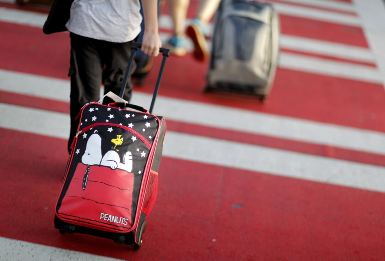 A child pulls a suitcase at Hartsfield-Jackson Atlanta International Airport ahead of the 2017 Thanksgiving holiday. Parents may be feeling pressure to pay more money to sit with their young children on crowded planes.