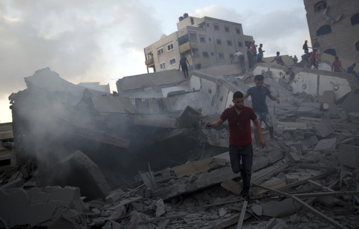 Palestinians inspect the damaged building of Said al-Mis’hal cultural center after it was hit bombed by an Israeli airstrike in Gaza City on Thursday. The Palestinian Health Ministry says several bystanders were wounded in Thursday evening’s airstrike in the Shati refugee camp.