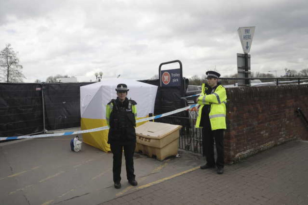 In this March 13, 2018, file photo, police officers guard a cordon around a police tent covering a supermarket car park pay machine near the spot where former Russian spy Sergei Skripal and his daughter were found critically ill following exposure to the Russian-developed nerve agent Novichok in Salisbury, England. The United States will impose sanctions on Russia for the country’s use of a nerve agent in an assassination attempt on a former Russian spy and his daughter. The State Department says Aug.