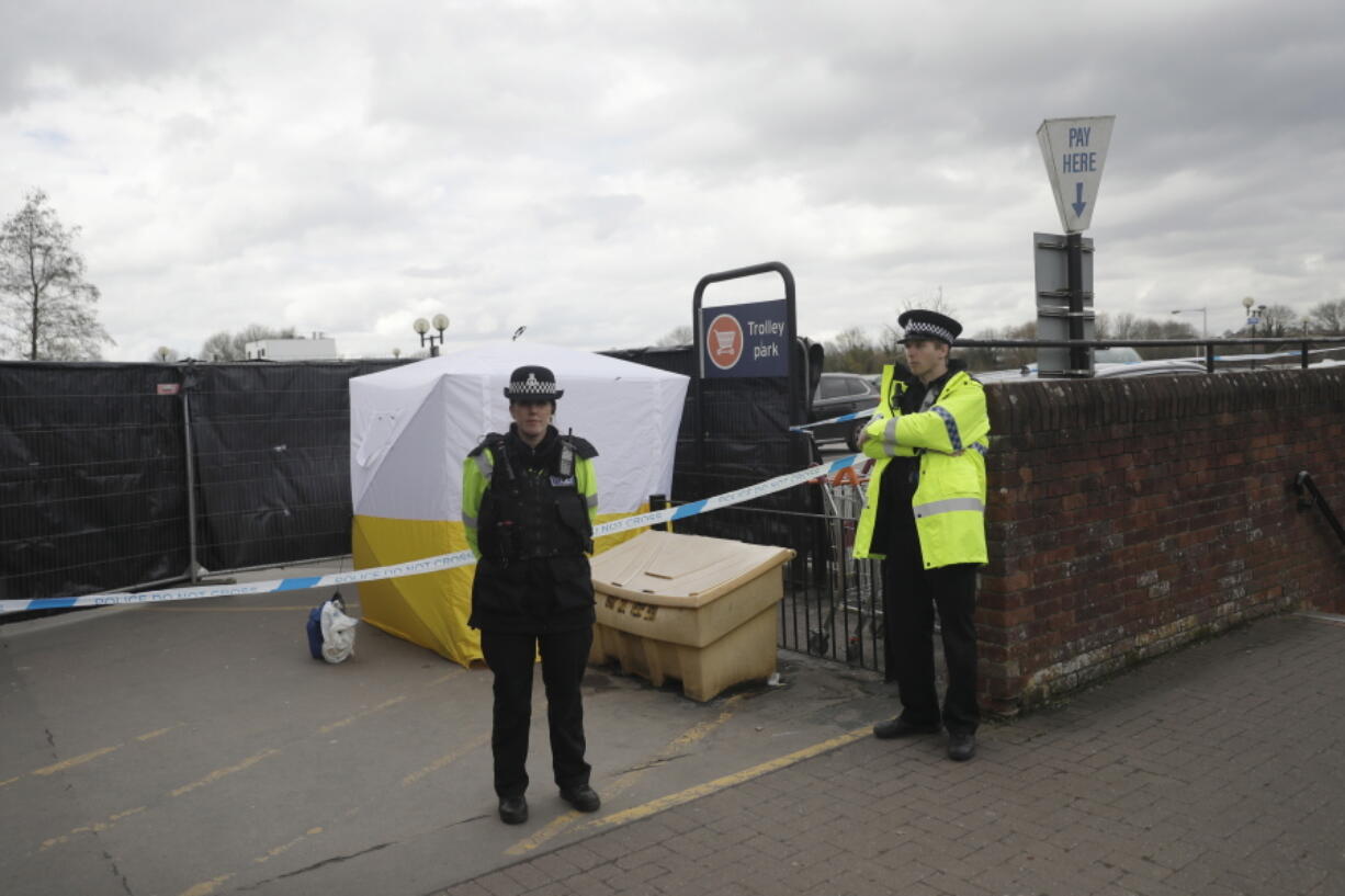 FILE - In this March 13, 2018, file photo, police officers guard a cordon around a police tent covering a supermarket car park pay machine near the spot where former Russian spy Sergei Skripal and his daughter were found critically ill following exposure to the Russian-developed nerve agent Novichok in Salisbury, England. The United States will impose sanctions on Russia for the country’s use of a nerve agent in an assassination attempt on a former Russian spy and his daughter. The State Department says Aug.