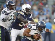 Seattle Seahawks quarterback Russell Wilson, right, is sacked by Los Angeles Chargers defensive end Melvin Ingram during the first half of an NFL preseason football game Saturday, Aug. 18, 2018, in Carson, Calif. (AP Photo/Jae C.