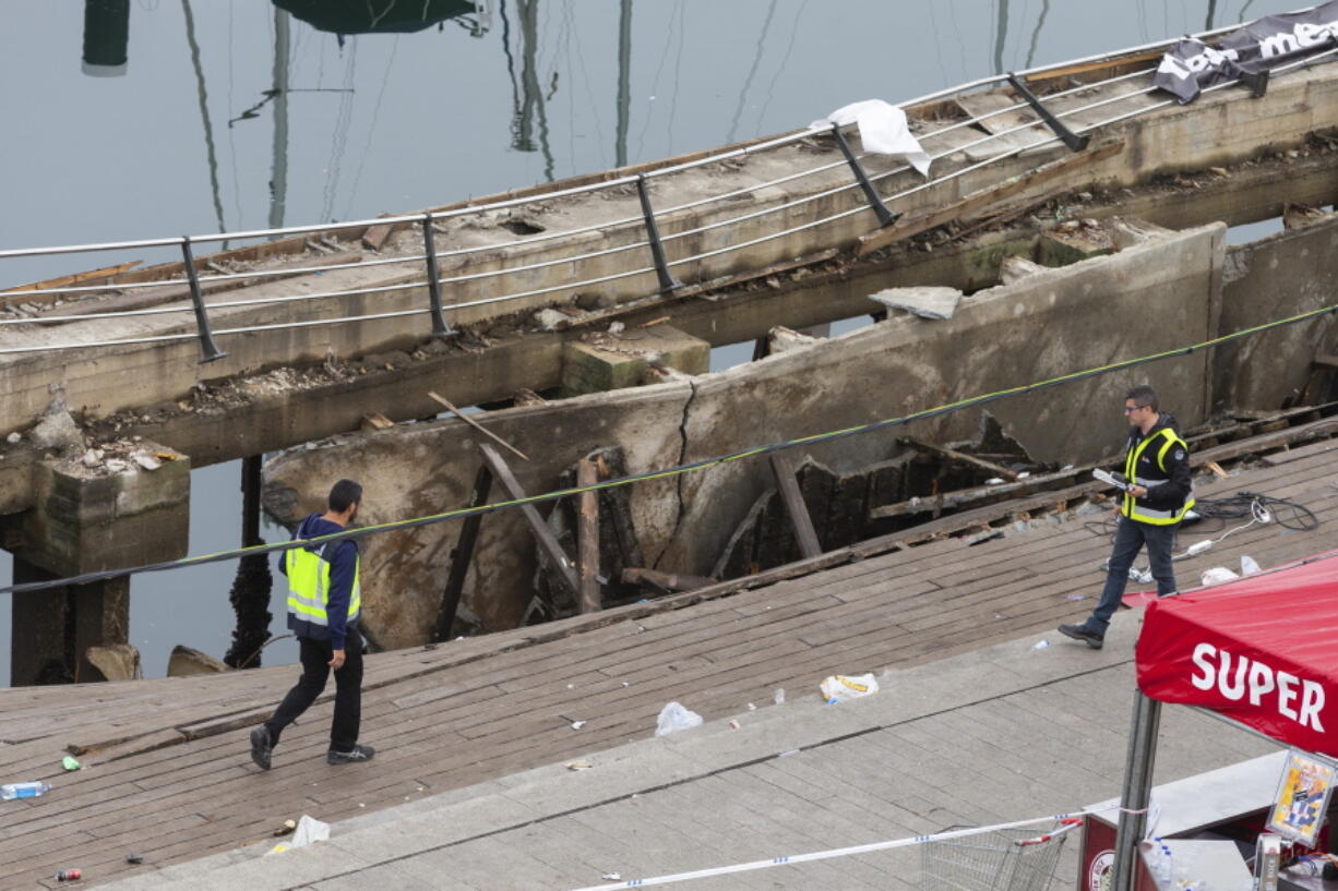 Two police officers work at the scene the day after an oceanside boardwalk collapsed during a nighttime concert in Vigo, Spain, on Monday. Authorities say the oceanside boardwalk collapsed around midnight Sunday at the closing event of a three-day festival, injuring 313 people, five of them seriously. (AP Photo/Lalo R.