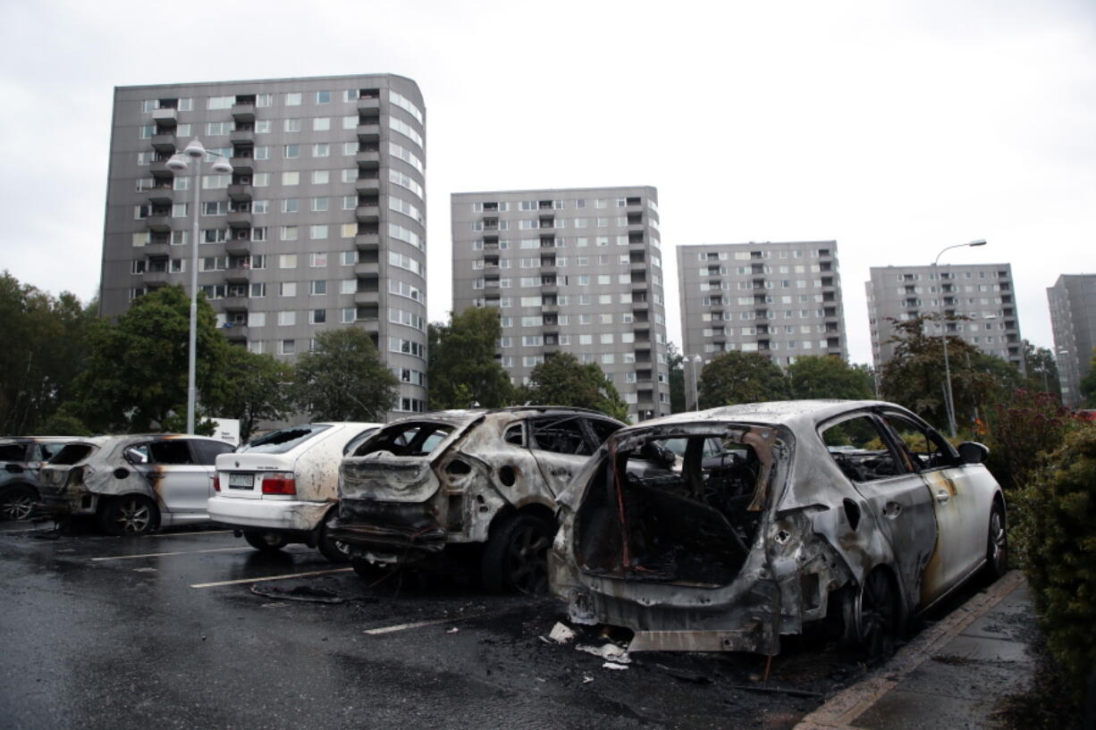 Burned cars are parked Tuesday at Frolunda Square in Gothenburg, Sweden. Masked youths torched dozens of vehicles overnight and threw rocks at police.