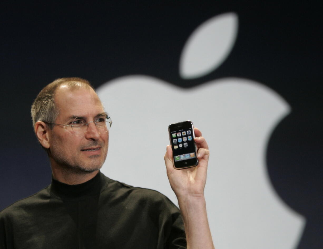 Apple CEO Steve Jobs holds up the new iPhone during his keynote address at MacWorld Conference & Expo in San Francisco in 2007. Apple has become the world’s first company to be valued at $1 trillion, the financial fruit of tasteful technology that has redefined society since two mavericks named Steve started the company 42 years ago.