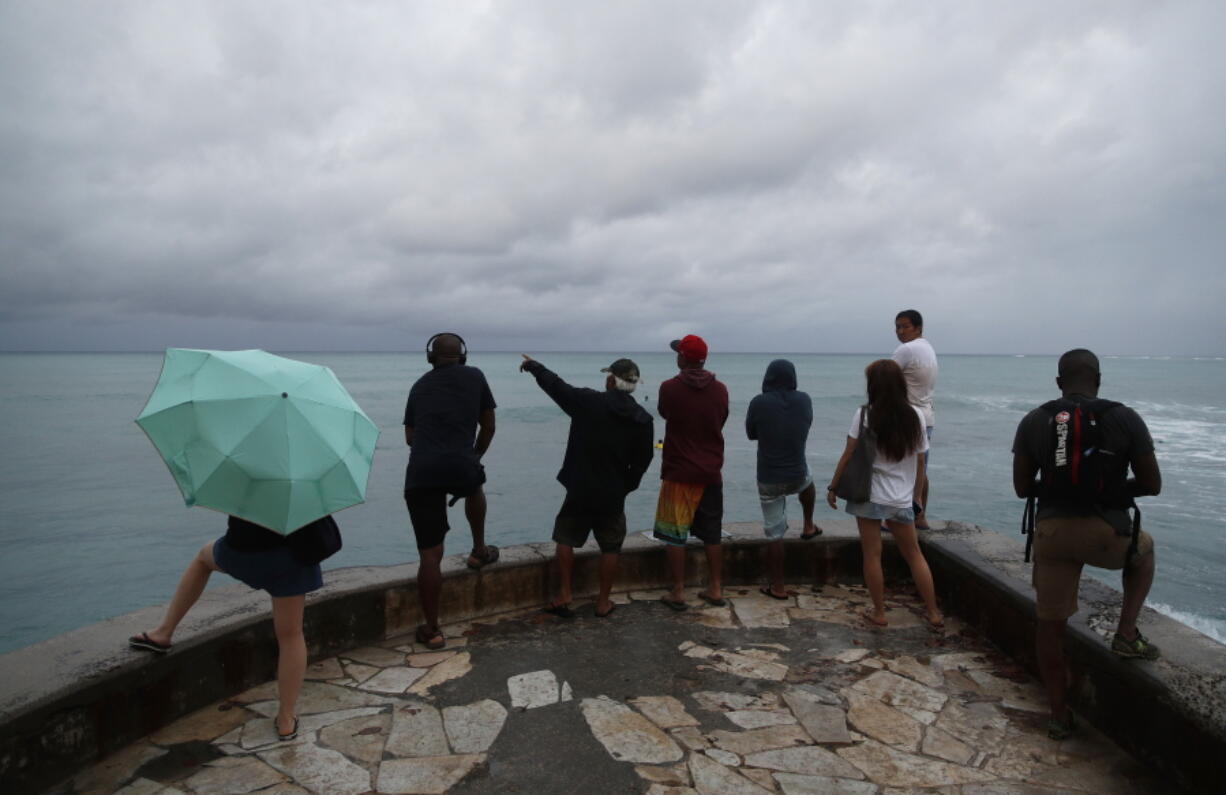 People look out over the ocean along Waikiki Beach in a light rain from Tropical Storm Lane in Honolulu on Saturday.