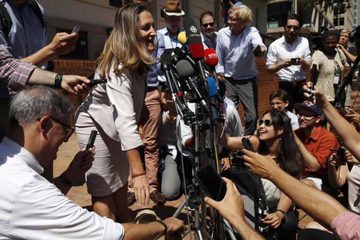 Noting the heat, Canada’s Foreign Affairs Minister Chrystia Freeland puts down a grocery bag holding popsicles for the media waiting outside of the Office of the United States Trade Representative, Thursday, Aug. 30, 2018, as trade talks continue in Washington.