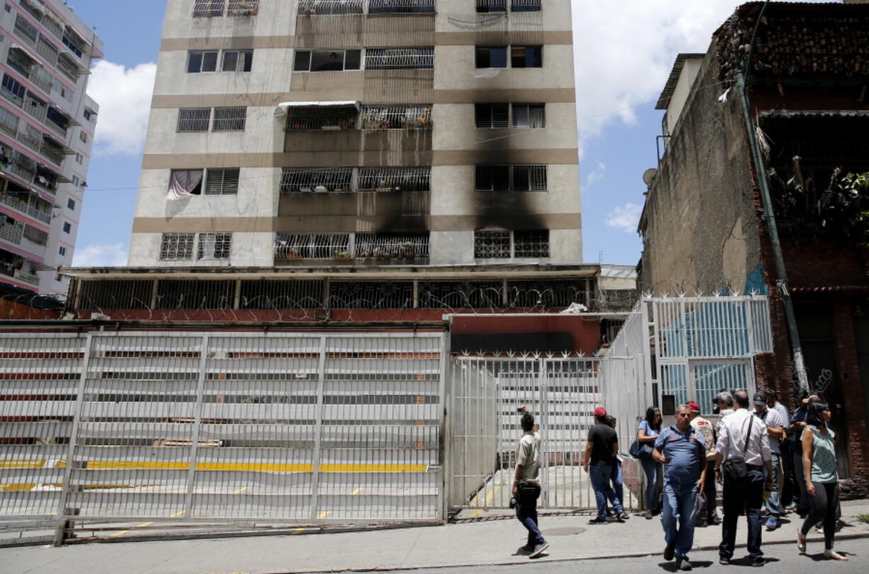 Press members wait as they try to get access to an apartment complex where an allegedly armed drone crashed, causing a fire, in Caracas, Venezuela, Sunday, Aug. 5, 2018. Venezuelan President Nicolas Maduro dodged an apparent assassination attempt the previous day when drones armed with explosives detonated while he was delivering a speech to hundreds of soldiers being broadcast live on television, according to officials.