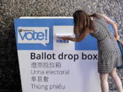 A voter places her ballot into a drop box Tuesday, Aug. 7, 2018, in Seattle. Washington voters will decide which candidates advance to the November ballot in 10 congressional races, a U.S. Senate seat and dozens of legislative contests in the state’s primary election Tuesday.