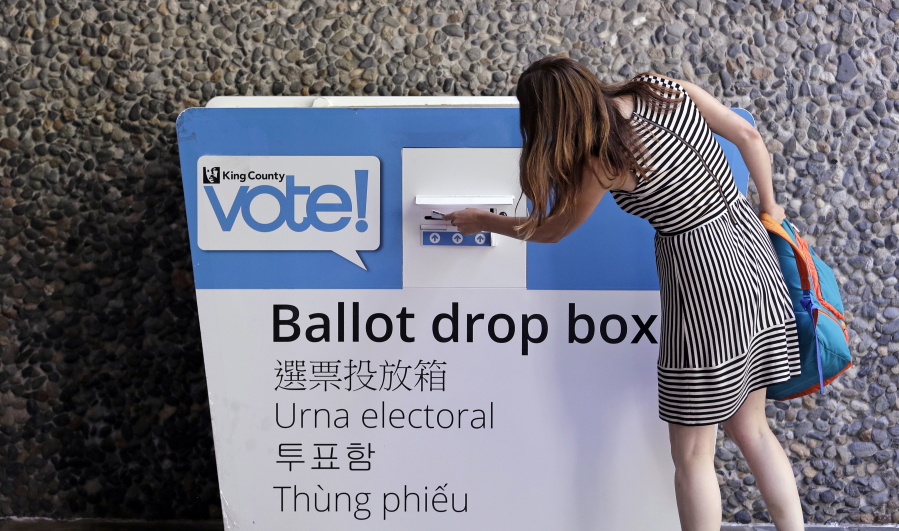 A voter places her ballot into a drop box Tuesday, Aug. 7, 2018, in Seattle. Washington voters will decide which candidates advance to the November ballot in 10 congressional races, a U.S. Senate seat and dozens of legislative contests in the state’s primary election Tuesday.