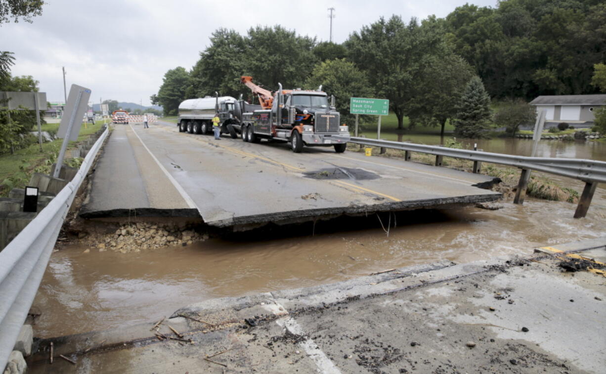 A milk truck was damaged early morning Tuesday, Aug. 21, 2018, when it fell into the missing section of a bridge over Highway 14 in Black Earth, Wis. More than 11 inches (28 centimeters) of rain fell overnight in places in or around Madison, according to the National Weather Service.