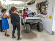 Family and friends watch as James Coen and Cristina Wardwell of Molalla, Ore., kiss to end their wedding ceremony at the drive-thru window of Mystic Gardens floral shop in Camas. Owner Leslie Rick started performing drive-thru weddings at her shop in January and has been marrying couples for more than 20 years.