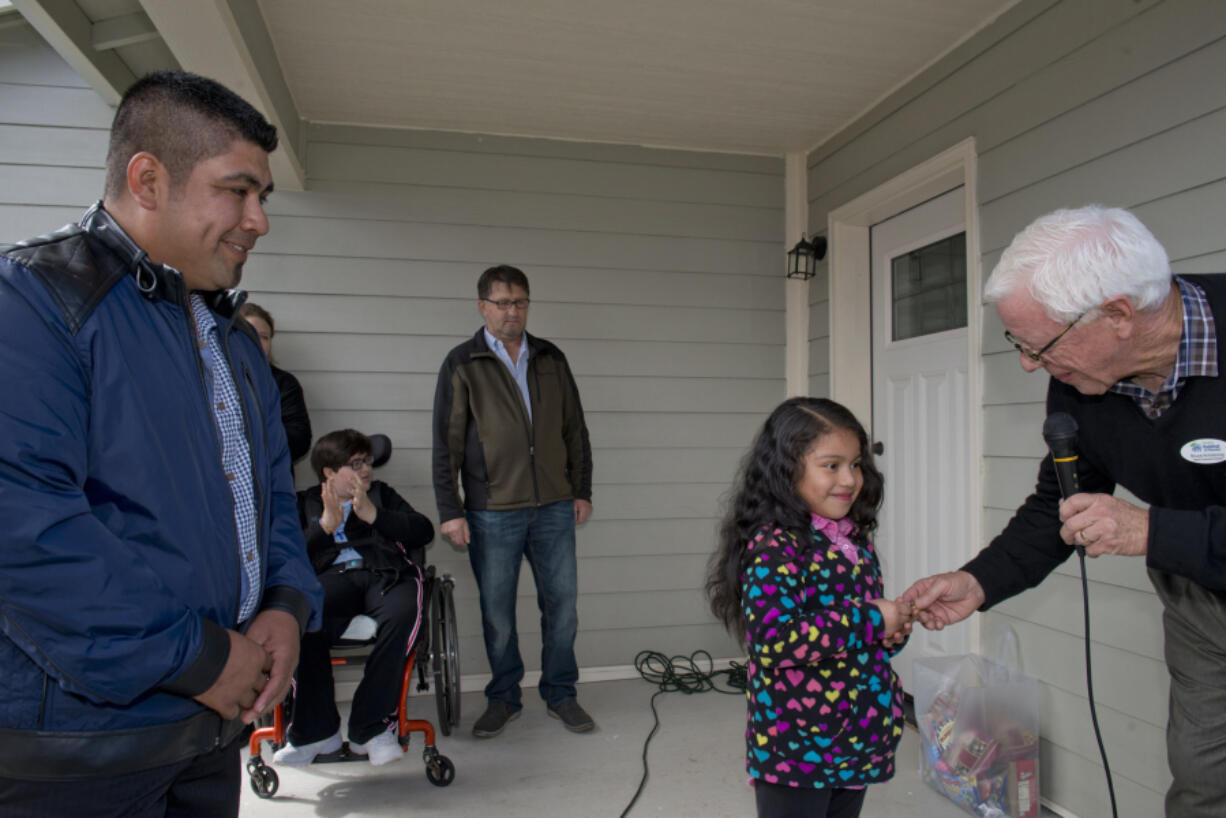 Reynaldo Ojeda, left, watches as Evergreen Habitat for Humanity’s Bruce Armstrong hands keys to Ojeda’s family’s new house to his daughter 6-year-old daughter, Leslie, Sunday afternoon.