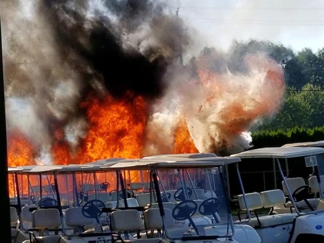 A fire burns brush and near golf carts at Club Green Meadows Tuesday afternoon.