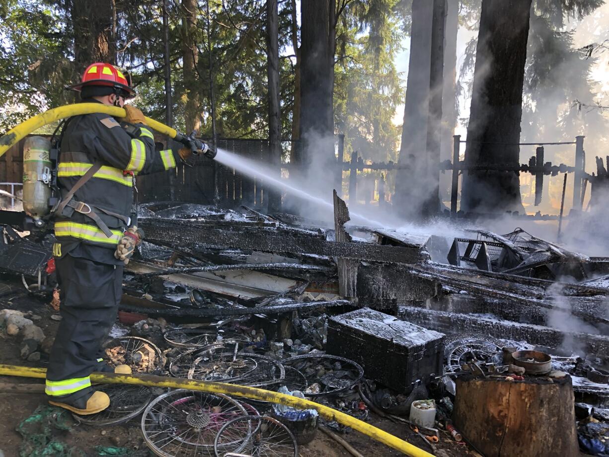 A Camas-Washougal Fire Department firefighter hoses down the remains of an outbuilding in that was destroyed by fire Friday. The blaze in the 2600 block of H Street is believed to have been caused by sparks from a grinder being used on a piece of metal.