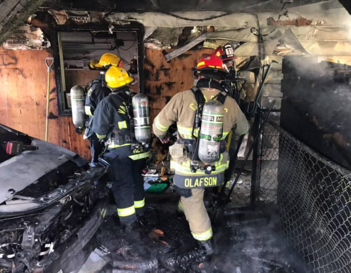 Vancouver Fire Department and Clark County Fire District 6 firefighters root through a garage Thursday afternoon in the Barberton area north of Vancouver.