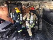 Vancouver Fire Department and Clark County Fire District 6 firefighters root through a garage Thursday afternoon in the Barberton area north of Vancouver.