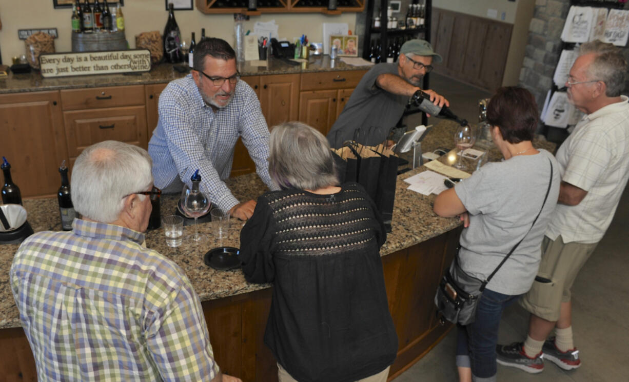 Owner Dave Kelly, behind the counter left of Bob Mayfield, serve customers wine at Windy Hills Winery in Ridgefield Sunday. The winery was a stop on the weekend’s wine and appetizer pairing events hosted by several local wineries.