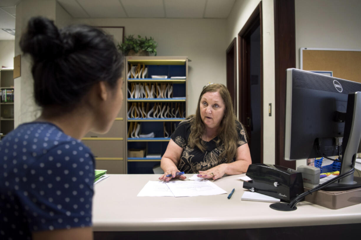 Connie Brown, a clerk in the Clark County Facilitator’s Office, right, helps Divine Cochran of Vancouver figure out paperwork and steps she needs to take in her divorce.