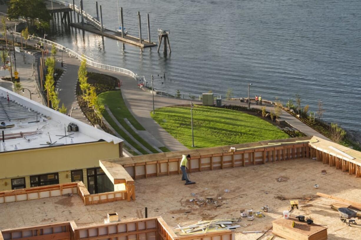 A construction worker sweeps debris along the top of a new building Sept. 11 at The Waterfront Vancouver, as the grass and other newly planted foliage flourish in the new park.