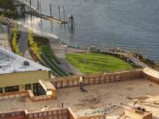 A construction worker sweeps debris along the top of a new building Sept. 11 at The Waterfront Vancouver, as the grass and other newly planted foliage flourish in the new park.