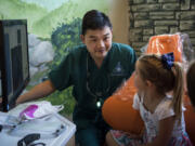 Dr. Ron Hsu looks over X-rays with patient Taryn Hatfield of Washougal, 6, center, and Taryn’s mom, Leah, at Storybook Dental in Camas. Hsu is working on a countywide program to help educate local schools on how to treat dental trauma and tooth avulsions.