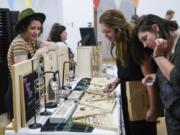 Kirsten Elise, left, a raw gemstone jewelry artist from Portland, helps customers Chantal Krystiniak, of Vancouver, and Elizabeth Meier, of Puyallup, pick out jewelry at Night Market Vancouver in 2018.