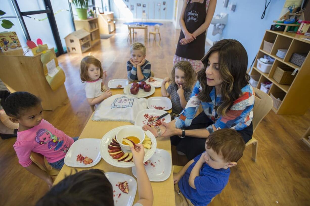 Tzivie Greenberg, right, director of The Gan Garrett Jewish Preschool, serves up apples and honey to children celebrating Rosh Hashanah, the Jewish New Year, a couple of days early. It will be year 5779, according to the Jewish calendar.