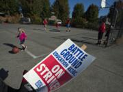 A strike sign is seen as children and teachers play basketball nearby at Marshall Park in Battle Ground on Friday, when striking teachers participated in a variety of community events.