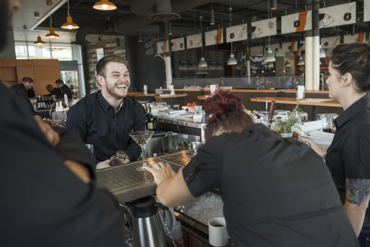 Nick Yahn of Battle Ground, a WildFin American Grill bartender, laughs while practicing menu cocktails with the rest of the bartending staff during training at The Vancouver Waterfront on Thursday morning.